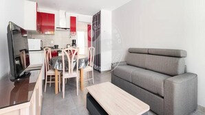 Un salon moderne avec un canapé gris, une table basse en bois et un coin repas comprenant une table et des chaises.