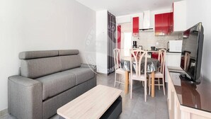 Un salon moderne avec un canapé gris, une petite table basse en bois et un coin repas comprenant une table et des chaises.