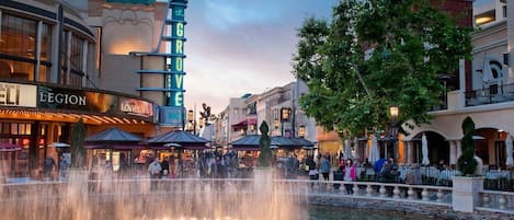 A public square with a fountain, surrounded by buildings with various shops and restaurants.