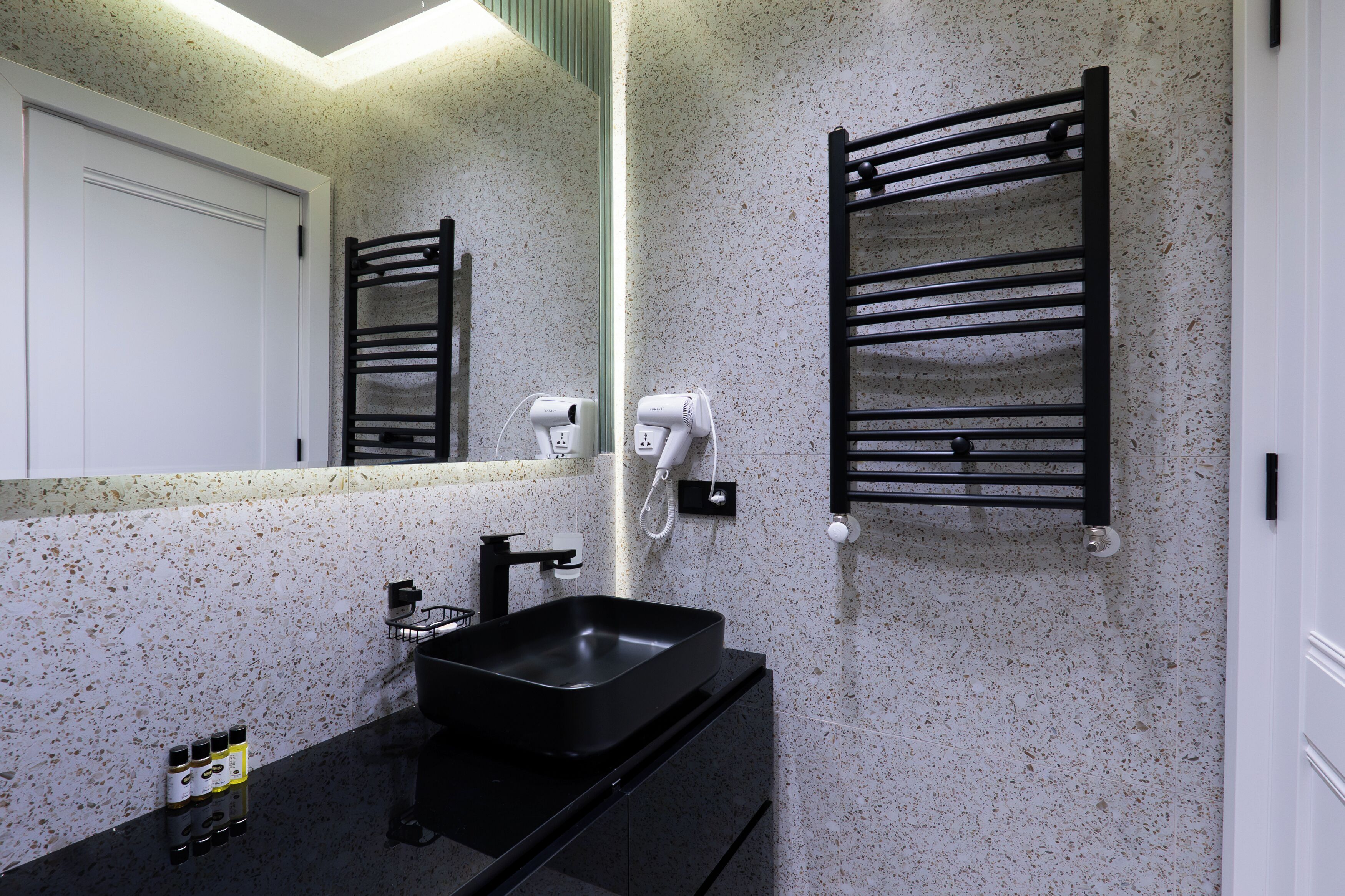 Un bagno con un lavandino nero, uno specchio e un portasciugamani.