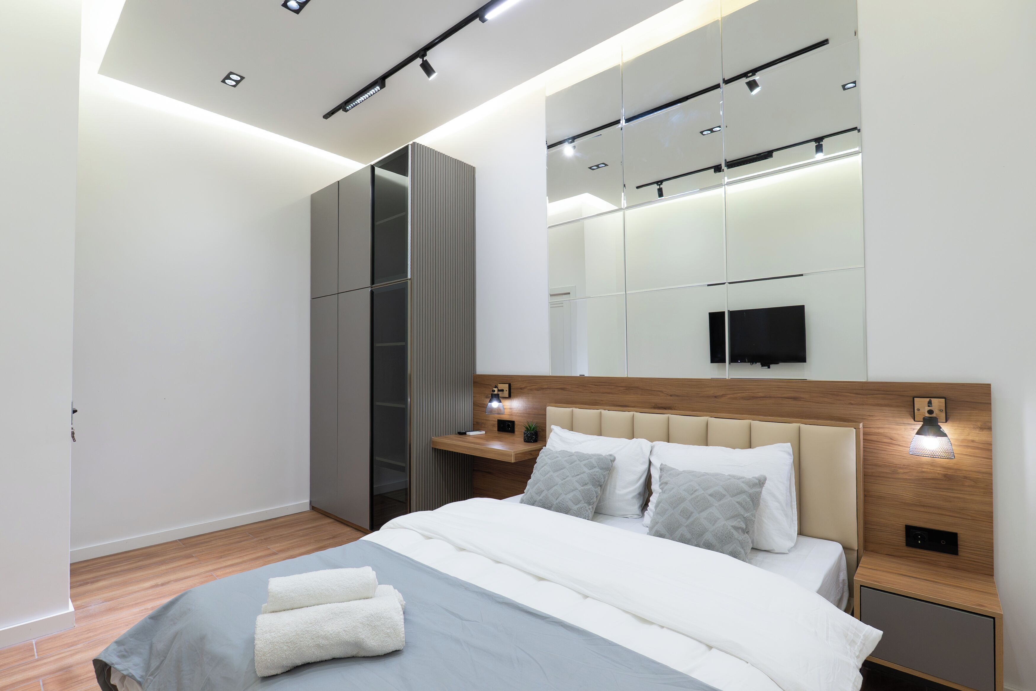 Une chambre moderne avec un lit, des tables de chevet, un miroir et un téléviseur.