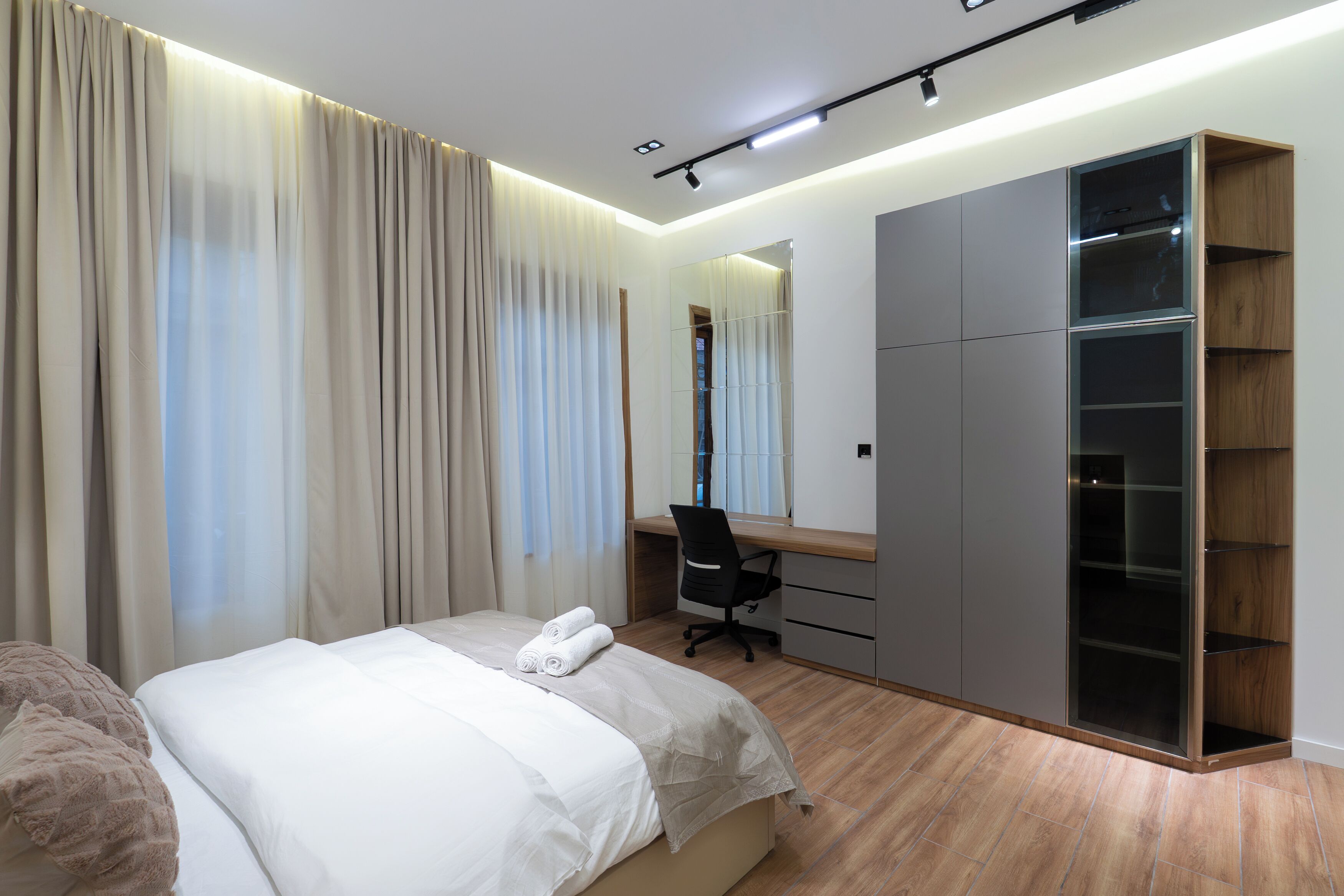 Een moderne slaapkamer met een bed, een bureau en een kledingkast.