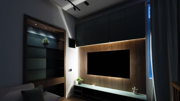 A modern living room with a large flat-screen TV mounted on a wooden panel wall, a built-in shelving unit, and a cozy seating area with a sofa and cushions. - Boutique 4BR House - Tbilisi Old Town (Tbilisi)