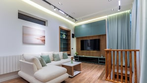 A modern living room with a sofa, coffee table, TV, and wooden flooring. - Boutique 4BR House - Tbilisi Old Town (Tbilisi)