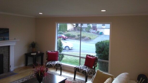 A living room with a fireplace, two patterned chairs, a sofa, and a large window overlooking a street. - Charming Redmond 3-bedroom house with AC in a pleasant neighborhood- Sleeps 8 (Redmond)