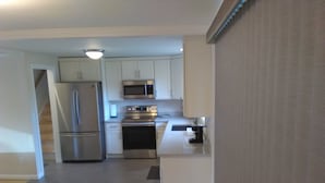 A modern kitchen with stainless steel appliances, white cabinetry, and a central island. - Charming Redmond 3-bedroom house with AC in a pleasant neighborhood- Sleeps 8 (Redmond)