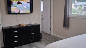 A bedroom with a bed, a TV on a dresser, a door, and a window. - Charming Redmond 3-bedroom house with AC in a pleasant neighborhood- Sleeps 8 (Redmond)