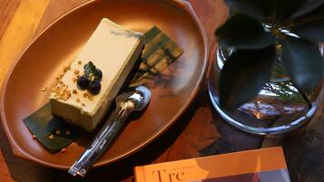 A dessert on a plate, a book, and a plant on a wooden table.