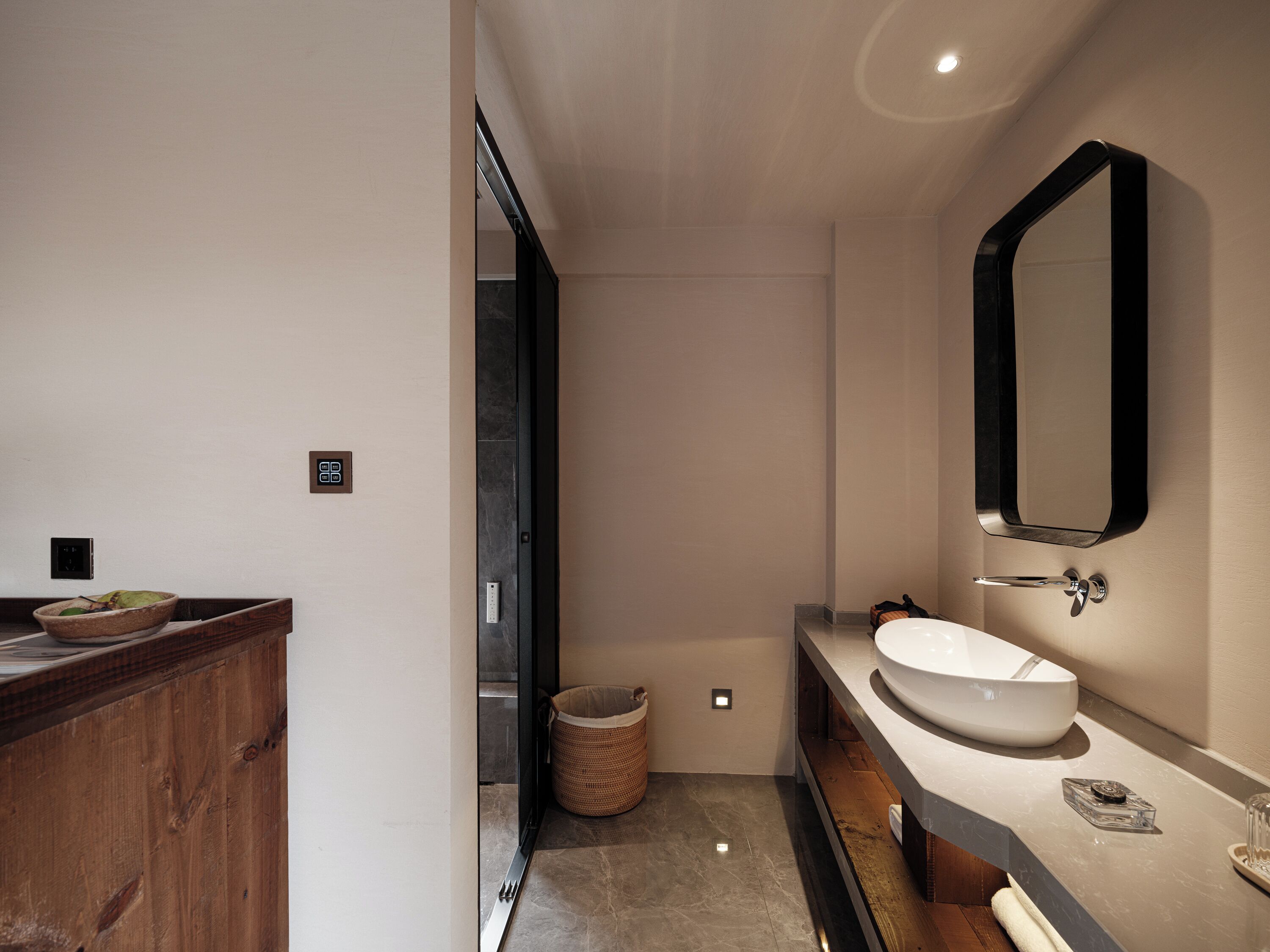 A modern bathroom with a wooden vanity, a large mirror, and a white sink.