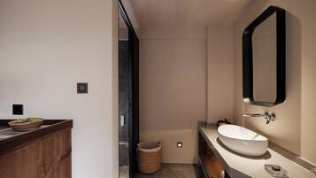 A modern bathroom with a wooden vanity, a large mirror, and a white sink.