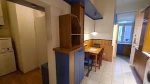 A compact kitchen with a dining area, a built-in wooden cabinet, and a window providing natural light. - Simple Room Long Stay Central Location (Vienna)