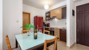 A modern kitchen with wooden cabinets, a red refrigerator, and a dining area with a glass table and chairs. - Ares 14 - Modern apartment with sea view, quiet location and close to the beach 20 m. (Umag)