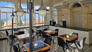 Ένα εστιατόριο με τραπέζια και καρέκλες, έναν πάγκο και θέα στην πόλη.