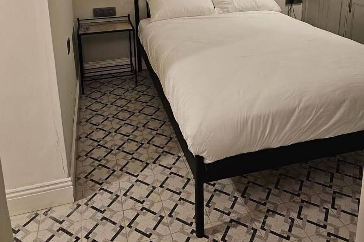 Un dormitorio con cama, mesita de noche, lámpara y armario.