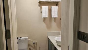 A compact bathroom with a toilet, sink, and towel rack.