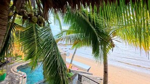 Un espace piscine agrémenté de palmiers et offrant une vue sur la plage.