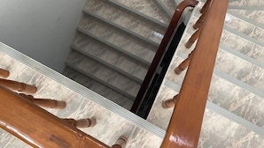 Una escalera con barandilla de madera y peldaños de mármol.