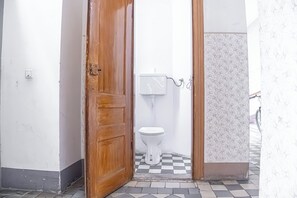 A bathroom with a white toilet, a tiled floor, and a wooden door. - Cozy 1BR Long Stay Near Waldmullerpark (Vienna)