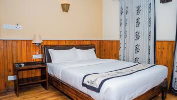 A wooden-framed bed with white bedding, a bedside table, a lamp, and a wall-mounted light fixture.