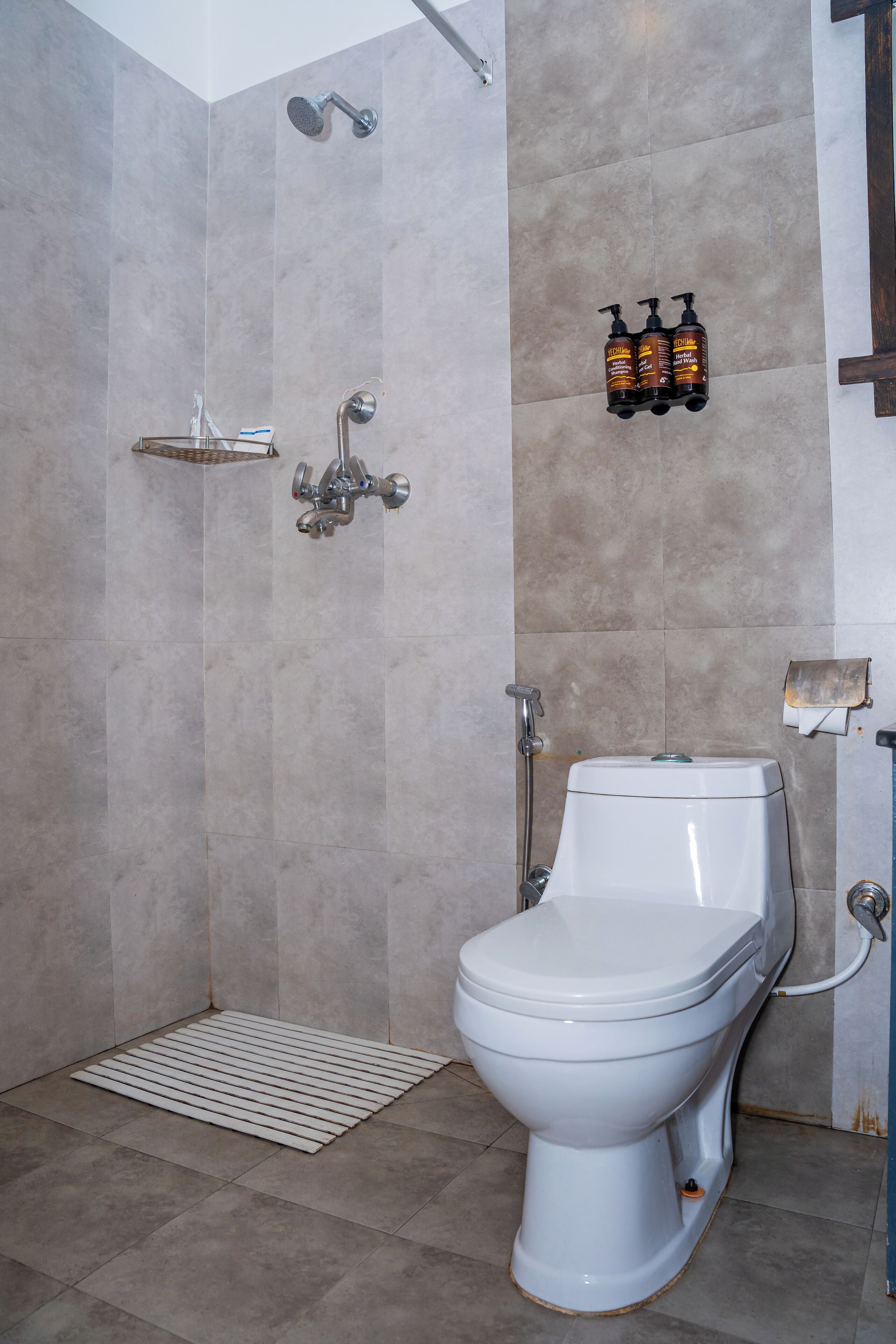 Une salle de bain avec douche, toilettes et une étagère contenant des articles de toilette.