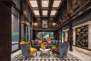 A spacious lobby with a large green sofa, two patterned armchairs, a coffee table, and a bookshelf filled with books and decorative items. - Friendly 2BR in Phuket Central With Pool & gym (Wichit)