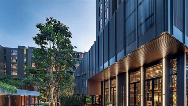 A modern hotel with a courtyard, large windows, and a well-lit entrance. - Friendly 2BR in Phuket Central With Pool & gym (Wichit)