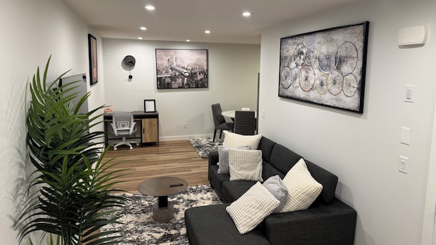 Een moderne woonkamer met een bank, salontafel en een grote kamerplant.