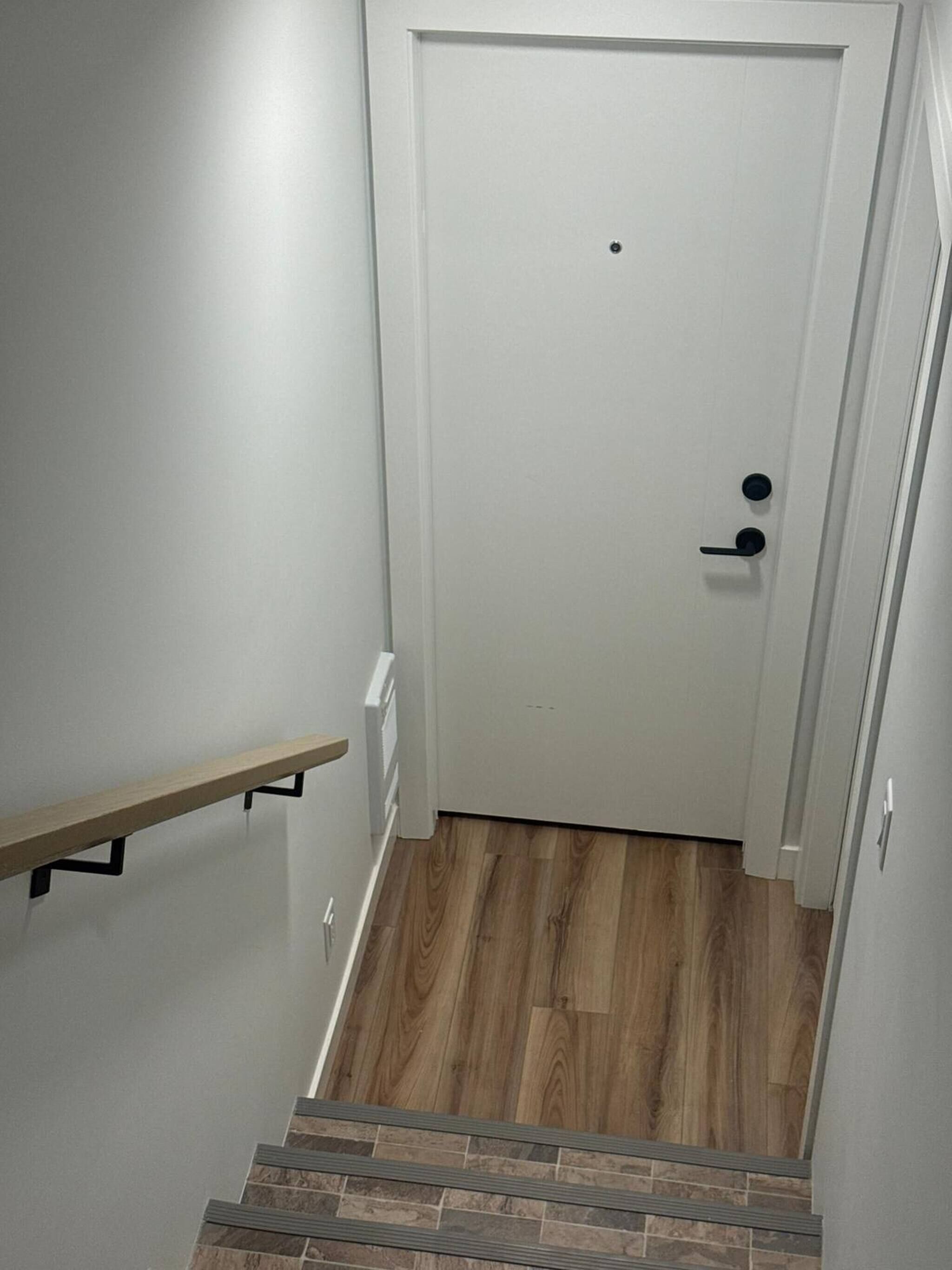 A staircase leading to a white door with a black handle and a small hole above it.