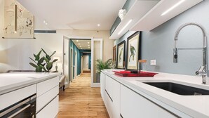 Una cucina moderna con mobili bianchi, un lavello in acciaio inossidabile e un pavimento in legno.