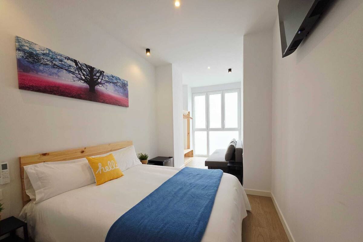 Een hotelkamer met een bed, een schilderij, een televisie en een raam.