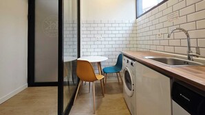 A compact kitchen with a washing machine, a sink, and a small dining area with chairs.