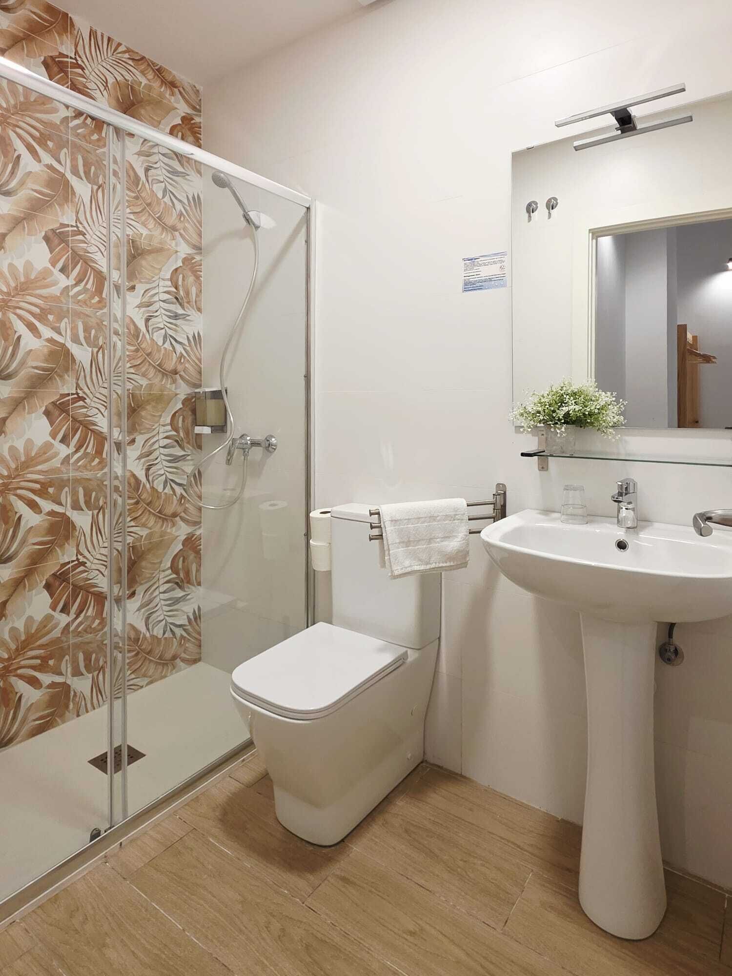 Un baño con cabina de ducha de vidrio, inodoro, lavabo y espejo.