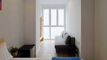 Ein Schlafzimmer mit Bett, einer Bank, einem kleinen Tisch, einer Pflanze und einem Fenster mit Blick.