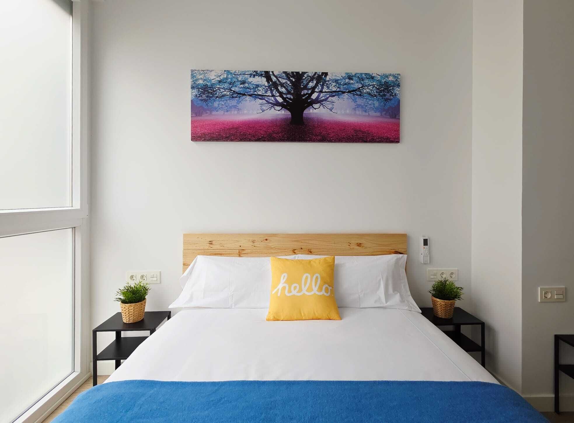 Een slaapkamer met een bed, een hoofdbord, een aan de muur hangend schilderij, nachtkastjes en een raam.