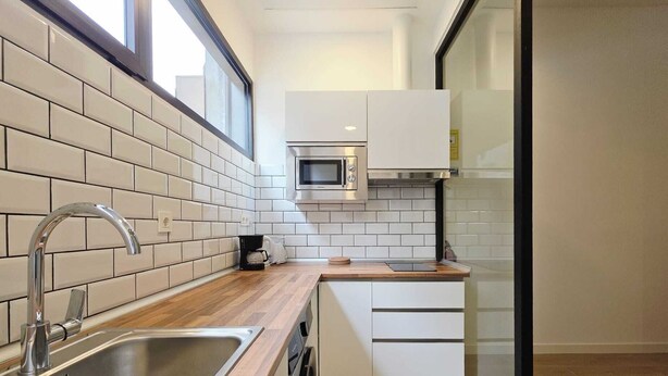 A modern kitchen with a stainless steel sink, a microwave, and a coffee maker on the counter.