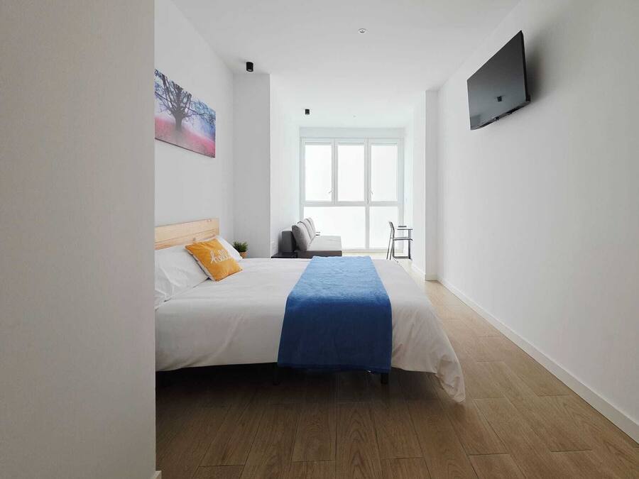 Habitación de hotel con cama, televisor en la pared, ventana y vistas al exterior.