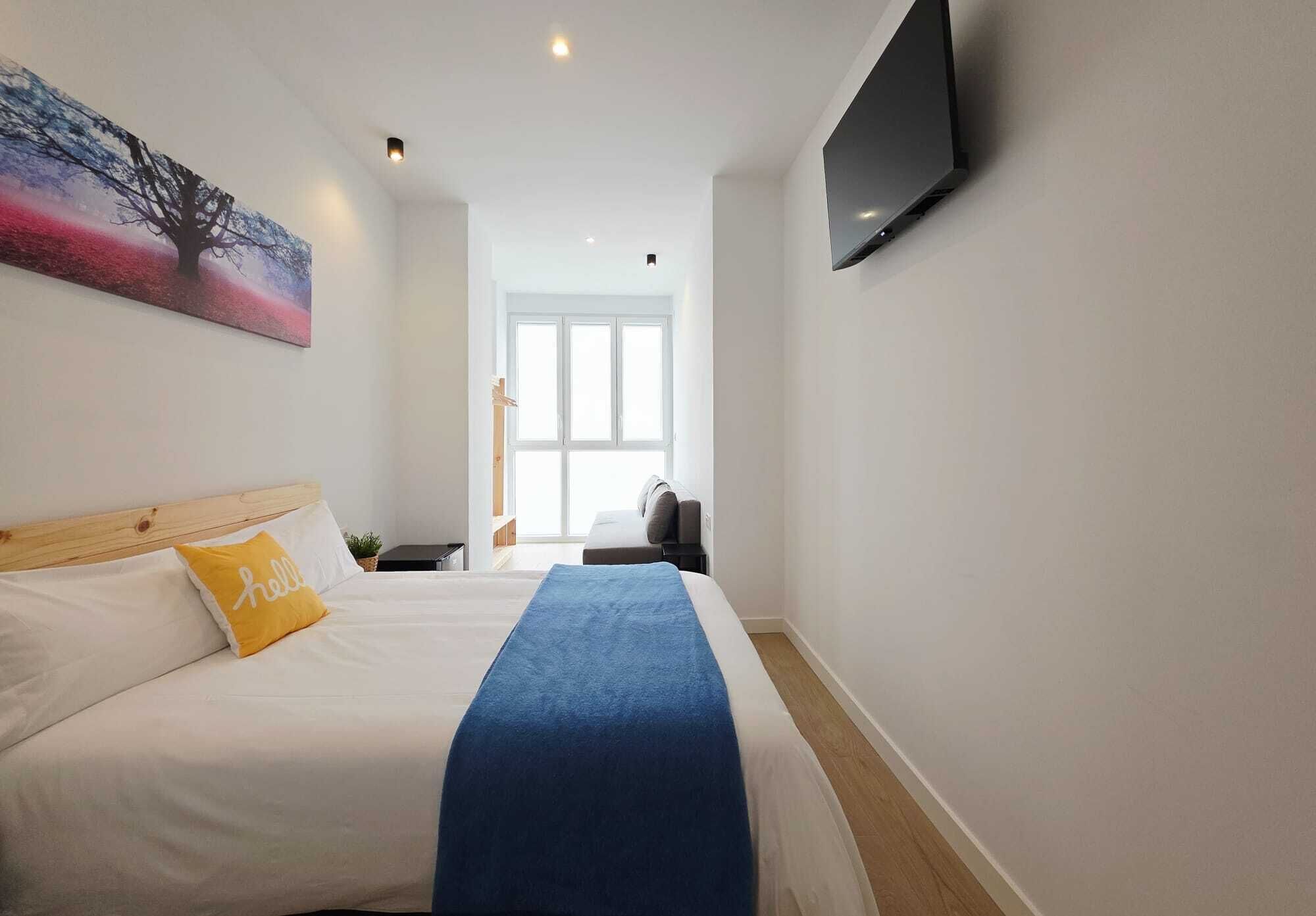 Quarto de hotel com uma cama, uma televisão fixada na parede e um quadro sobre a cama.
