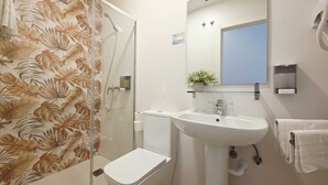 A bathroom with a shower, toilet, sink, and a mirror.