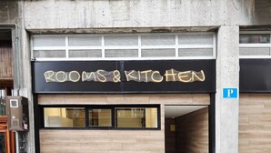 A building with a sign reading 'ROOMS & KITCHEN' and a parking sign.