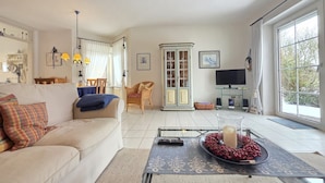 Una sala de estar con sofá, mesa de comedor, televisor y aparador.