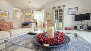 Una sala de estar con un sofá, una mesa de centro con un adorno decorativo, un televisor y un aparador.