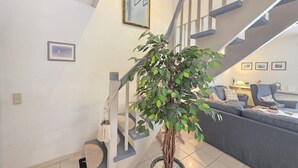 Un escalier orné d’un pot de fleurs, un canapé gris et un tableau encadré accroché au mur.