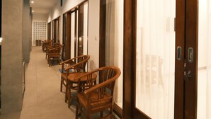 A corridor with wooden chairs and tables, a sliding door, and a tiled floor. - Clean & Affordable Homestay in South Kuta. Simple, Cozy, and Convenient (Badung)