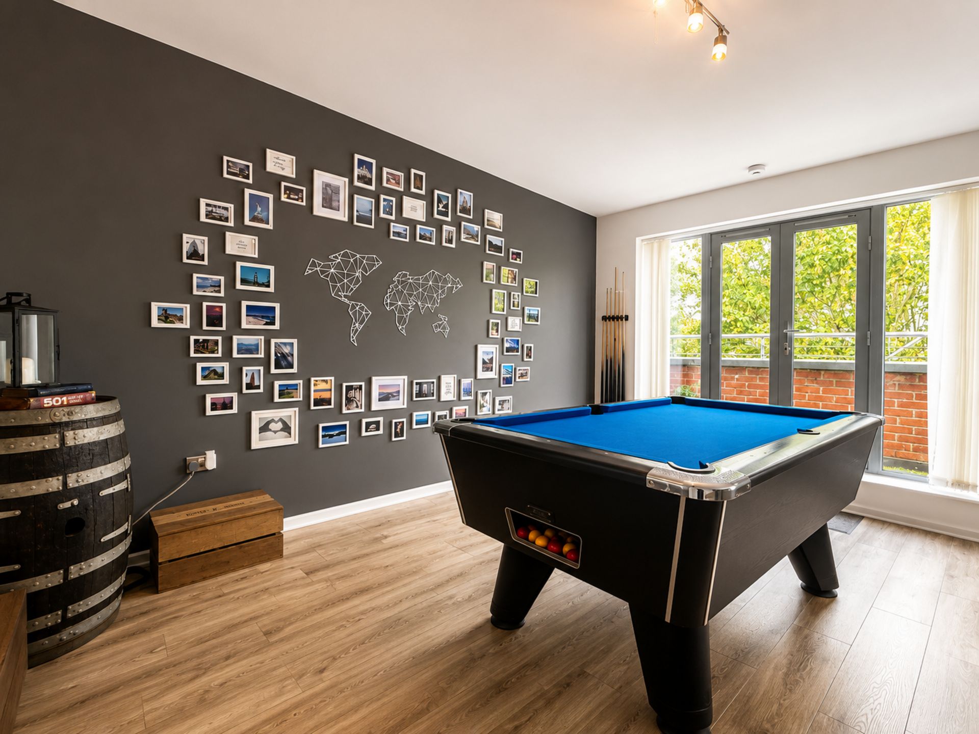 Una mesa de billar en una habitación con un mural de un mapa mundial y un ventanal grande.
