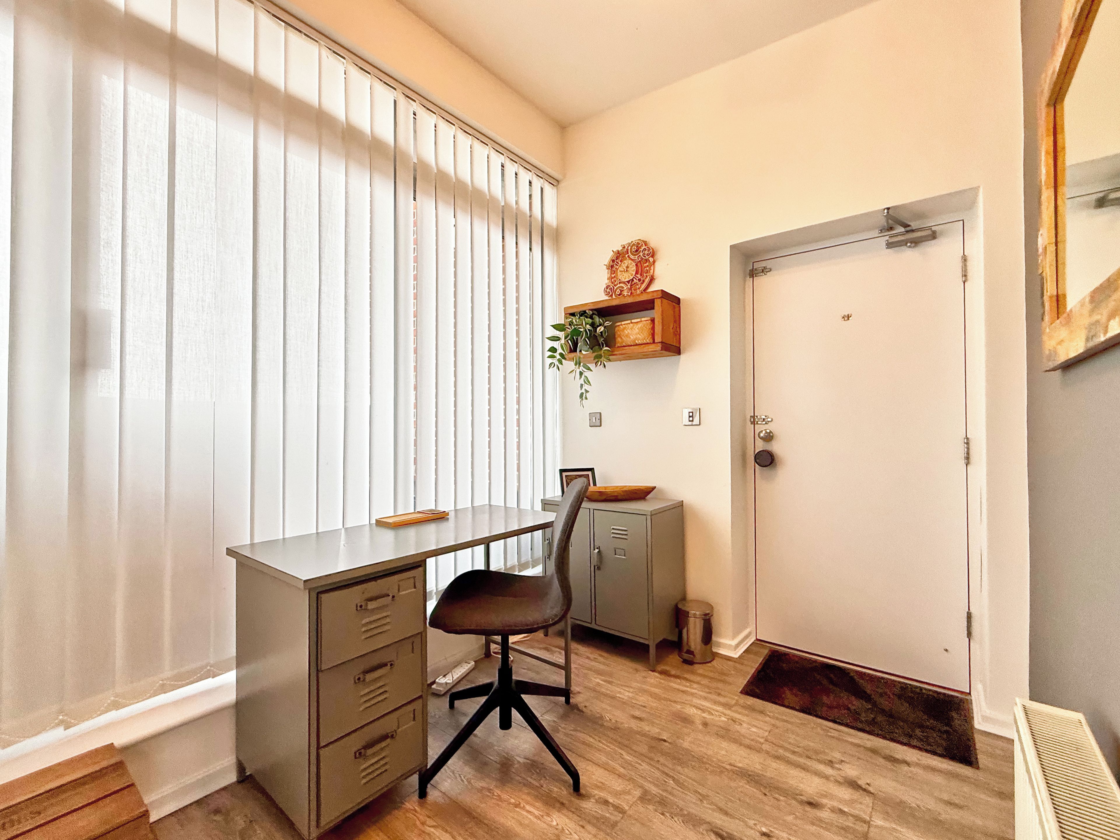 Una habitación con escritorio, silla, archivador y puerta.