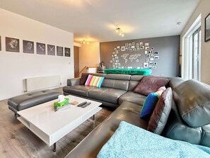 Un salon moderne avec un canapé d’angle, une table basse blanche et une décoration murale représentant une carte du monde.