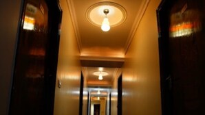 Un couloir avec un luminaire au plafond et des portes de part et d’autre.