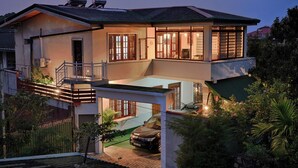 A two-story house with a balcony, a car parked in the driveway, and a well-maintained garden. - Cozy 2-bedroom apartment in serene Kandy with AC (Kandy)