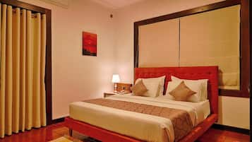 Habitación de hotel con una cama grande, una mesita de noche, una lámpara, un cuadro en la pared y una ventana con cortinas.