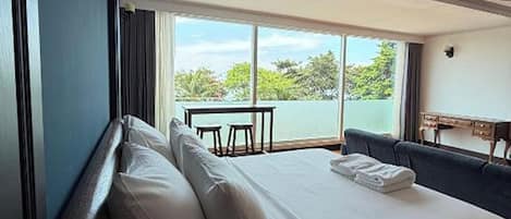 A hotel room with a large bed, a view of the outdoors, and a seating area with a table and chairs.